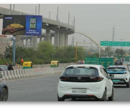 Large outdoor billboard by Acme Advertiser displayed on a busy roadside, showcasing high-impact hoarding advertising for brand visibility in urban India.