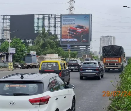 Toyota Urban Cruiser Taisor SUV advertisement displayed on a large billboard above a busy Indian highway with multiple cars and buildings in the background.