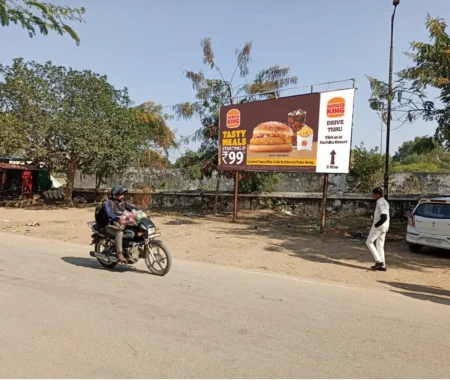 Burger King ₹99 meal hoarding with burger, fries, and coke, showing direction to drive-thru near Radhika Resort on an Indian roadside.