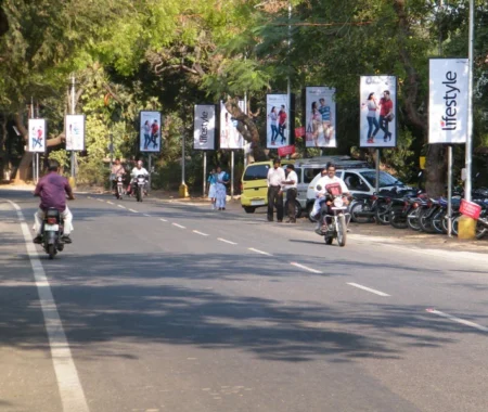 Pole kiosk advertisements for Lifestyle clothing store displayed along a tree-lined urban road, showcasing fashion branding through outdoor media in India.