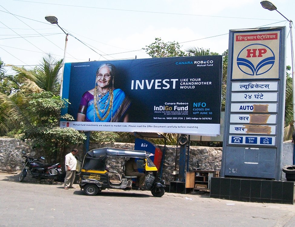 Petrol pump advertising for Canara Robeco Indigo Fund featuring elderly woman visual and NFO promo targeting fuel station visitors.