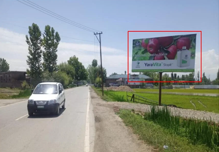 Rural roadside in Himachal Pradesh with 20x10 ft YaraVita Stopit hoarding by ACME Advertising Co., featuring red apples and agricultural message; visible white vehicle, greenery, trees, and clear sky.