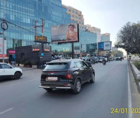 HSJ Platinum hoarding by ACME Advertising Co. in Jammu, featuring woman in ethnic wear on busy city road.